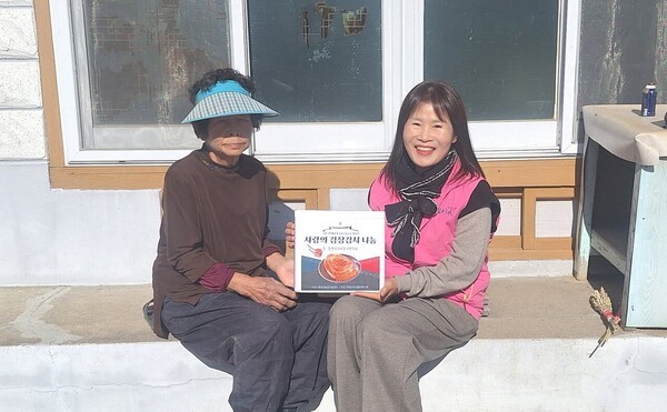 행복선생님이 어르신에게 김장김치를 전달하고 있다. 