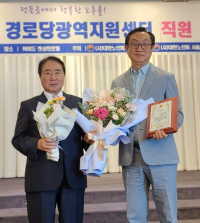 김용명 부산연합회 센터장(오른쪽)이 공로패를 받고 이석현 상임부회장과 기념촬영을 하고 있다.